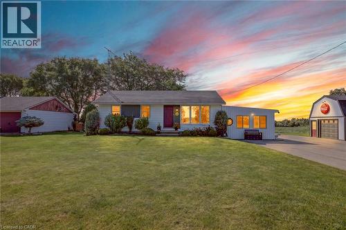 White ranch-style home featuring a dark shingle roof, well-maintained front lawn, and mature landscaping - 184726 Cornell Road, Tillsonburg, ON - Outdoor
