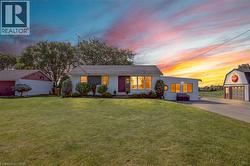 White ranch-style home featuring a dark shingle roof, well-maintained front lawn, and mature landscaping - 