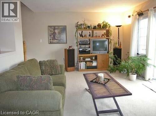 Bright living space featuring light-colored carpeting, neutral wall tones, and a large window with vertical blinds - 151 Clairfields Drive E Unit# 39, Guelph, ON - Indoor Photo Showing Living Room