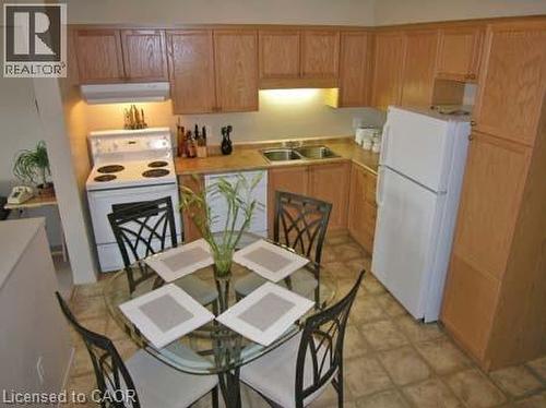 Kitchen featuring abundant wood-finish cabinetry, a dual basin stainless steel sink, and a full-size refrigerator - 151 Clairfields Drive E Unit# 39, Guelph, ON - Indoor Photo Showing Kitchen With Double Sink