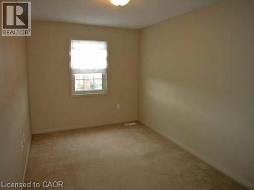 Carpeted interior room featuring neutral wall tones, a double-hung window with trim, and a ceiling-mounted light fixture - 151 Clairfields Drive E Unit# 39, Guelph, ON - Indoor Photo Showing Other Room