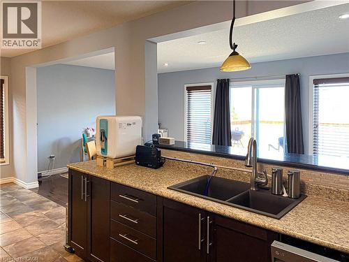 Kitchen featuring dark wood-finish cabinetry with silver-tone hardware, a dual-basin sink with a gooseneck faucet, and light-toned countertop - 180 Huck Crescent, Kitchener, ON - Indoor Photo Showing Kitchen With Double Sink