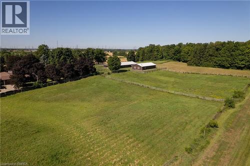 Expansive green acreage featuring a large brown barn with a light-colored roof, multiple fenced paddocks, and mature tree lines bordering the property - 269 Brant County Road 22, Ancaster, ON - Outdoor With View