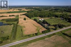 Expansive rural property featuring cultivated fields, mature tree lines, a private pond, and multiple outbuildings - 