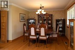 Formal dining space featuring wood-finish flooring, crown molding, and a chandelier with multiple light sources - 