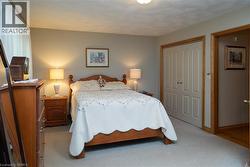 Bedroom with light-colored carpeting, neutral wall paint, and a window featuring sheer white curtains - 