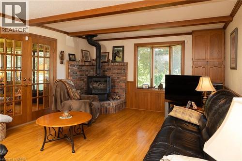 Living area featuring wood-finish flooring, exposed ceiling beams, and a brick-surround wood-burning stove with a stone hearth - 269 Brant County Road 22, Ancaster, ON - Indoor Photo Showing Living Room With Fireplace