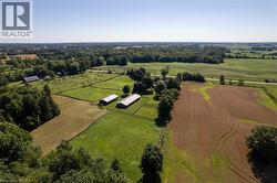Expansive agricultural property featuring multiple fenced pastures, two large outbuildings with light-colored roofs, and cultivated fields - 