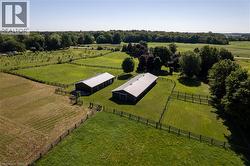 Expansive rural property featuring two dark-toned barns with light-colored roofs, surrounded by lush green pastures and mature trees - 