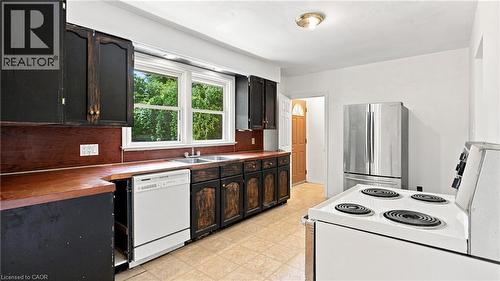 Kitchen featuring wood-finish countertops, black cabinetry, a double-basin sink, and a white dishwasher - 524 Dorval Drive, Ancaster, ON - Indoor Photo Showing Kitchen With Double Sink