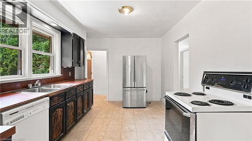 Kitchen featuring a dual basin stainless steel sink, wood-finish countertops, dark cabinetry, and a white electric range - 524 Dorval Drive, Ancaster, ON - Indoor Photo Showing Kitchen With Double Sink