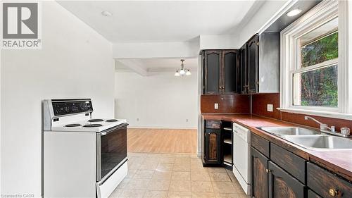 Kitchen featuring dark wood cabinetry, a white electric range, a double basin stainless steel sink, and a dishwasher - 524 Dorval Drive, Ancaster, ON - Indoor Photo Showing Kitchen With Double Sink