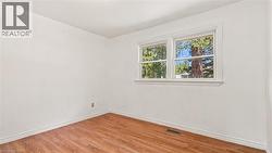 Room with wood-finish flooring, white walls, and white baseboards - 