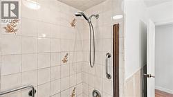 Tiled shower with handheld shower fixture and chrome grab bars - 