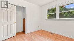 Bright interior space featuring wood-finish flooring, white baseboards, and white walls - 