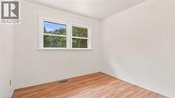 Room featuring light-colored walls, wood-finish flooring, white baseboards, and a white-framed window - 