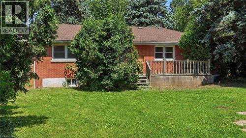 Brick exterior residence featuring a wood-tone deck with railing, a brown shingle roof, and multiple windows - 524 Dorval Drive, Ancaster, ON - Outdoor