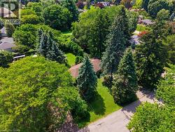 Property surrounded by mature trees, featuring a gabled roofline and green lawn areas - 