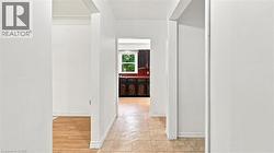 Hallway with neutral wall tones and diverse flooring, including light-toned wood-finish flooring and patterned floor tiles - 
