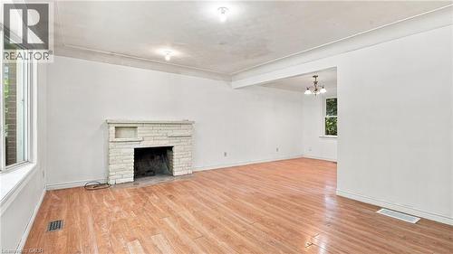 Spacious interior featuring wood-finish flooring, a stone-clad fireplace with mantel, and white walls - 524 Dorval Drive, Ancaster, ON - Indoor Photo Showing Other Room With Fireplace