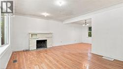 Spacious interior featuring wood-finish flooring, a stone-clad fireplace with mantel, and white walls - 