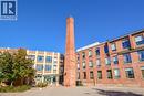 Brick facade building with a prominent brick chimney, multi-pane windows, and a covered entrance - 26 Ontario Street Unit# 127, Guelph, ON  - Outdoor 