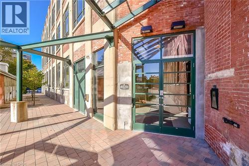 Brick facade building with a prominent glass entry door, dark green framing, and dual handles - 26 Ontario Street Unit# 127, Guelph, ON - Outdoor With Exterior