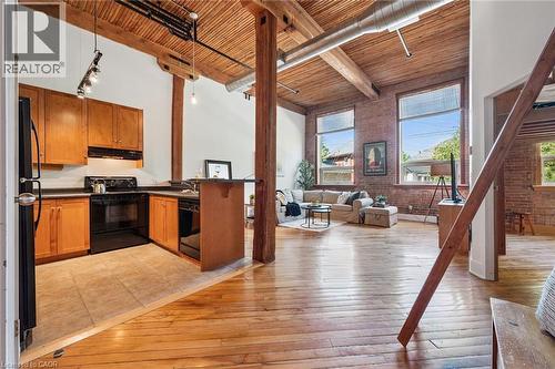 Open-concept living space featuring exposed brick walls, wood-finish flooring, and a unique wood-slat ceiling with visible ductwork - 26 Ontario Street Unit# 127, Guelph, ON - Indoor