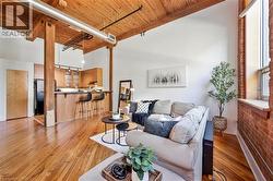 Open-concept living space featuring exposed wood beams, high wood plank ceilings, and polished wood flooring - 