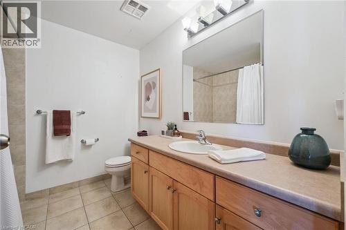 Bathroom featuring a single vanity with wood-finish cabinetry, a large mirror, and a shower-tub combination - 26 Ontario Street Unit# 127, Guelph, ON - Indoor Photo Showing Bathroom