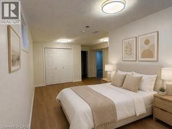 Spacious room featuring wood-finish flooring, white walls, and a large bi-fold closet - 
