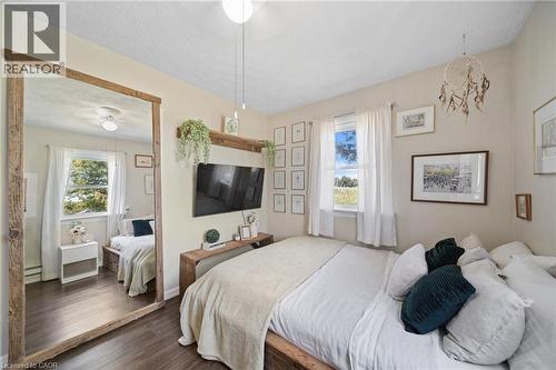 Interior room featuring wood-finish flooring, two large windows with white curtains, and a ceiling-mounted light fixture - 3 Bousfield Lane, Jarvis, ON - Indoor Photo Showing Bedroom