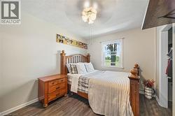 Bedroom featuring wood-finish flooring, a window with exterior views, and a ceiling fan with integrated lighting - 