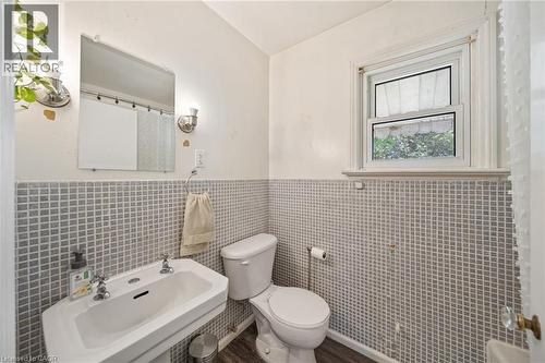 Pedestal sink with dual faucets, framed rectangular mirror, and wall-mounted light fixtures - 3 Bousfield Lane, Jarvis, ON - Indoor Photo Showing Bathroom