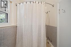 Bathtub with white subway tile surround, hand-held shower fixture, and an operable window - 