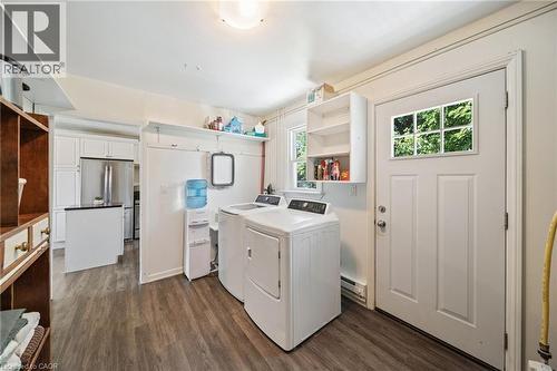 Utility area featuring wood-finish flooring, a white paneled door with glass inserts, a single window, and a built-in wall shelf - 3 Bousfield Lane, Jarvis, ON - Indoor Photo Showing Laundry Room