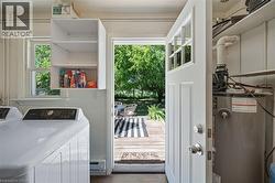 Laundry area featuring a top-load washing machine, wall-mounted cabinetry, and a window with natural light - 