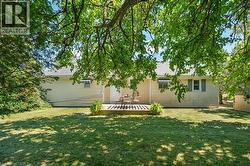 Spacious backyard featuring a manicured lawn and mature trees providing natural shade - 