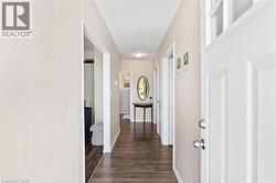 Entryway featuring a white paneled door with transom window, wood-finish flooring, and vertical wall paneling - 