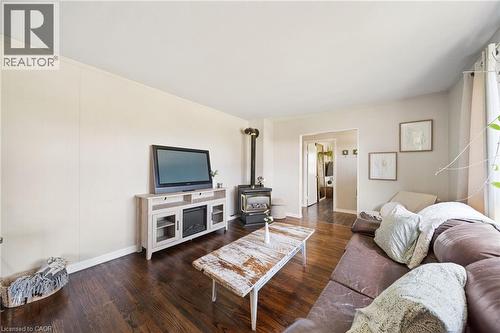 Living area featuring dark wood-finish flooring, a built-in wood-burning stove, and light-toned wall paneling - 3 Bousfield Lane, Jarvis, ON - Indoor Photo Showing Living Room