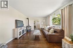 Living area featuring rich wood-finish flooring and white paneled walls - 