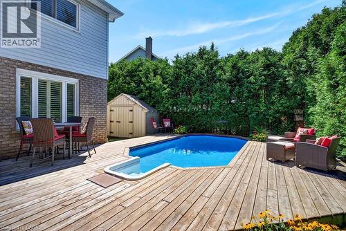 Backyard oasis featuring an in-ground pool, expansive wood deck, and tall privacy hedges - 5140 Crimson King Way, Beamsville, ON - Outdoor With Above Ground Pool With Deck Patio Veranda