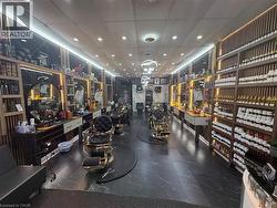 Commercial interior featuring dark-toned flooring, multiple workstations with integrated mirrors and lighting, extensive built-in shelving, and recessed overhead lighting - 