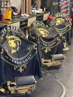 Commercial space featuring dark marbled-finish flooring and multiple barber chairs with gold-tone accents - 