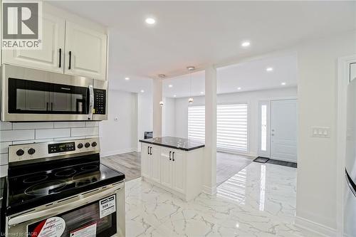 Kitchen featuring stainless steel appliances, white cabinetry with black hardware, and a white subway tile backsplash - 8 Marlborough Road, Guelph, ON - Indoor Photo Showing Kitchen