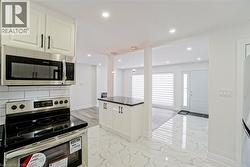 Kitchen featuring stainless steel appliances, white cabinetry with black hardware, and a white subway tile backsplash - 