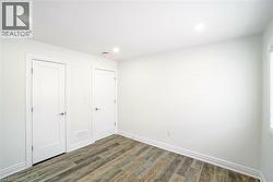 Interior room featuring wood-finish flooring, recessed lighting, and crisp white walls - 