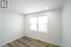 Bright window with zebra blinds, white trim, and wood-finish flooring - 
