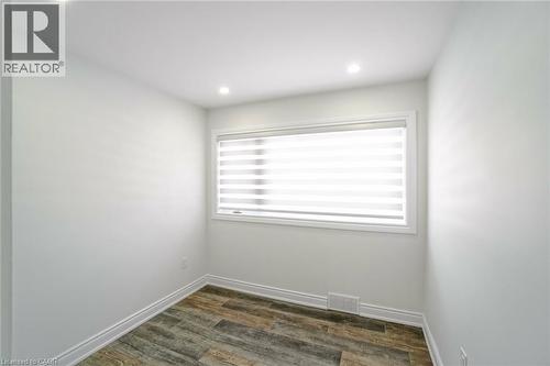 Neutral-toned room featuring wood-finish flooring, recessed lighting, and a window with horizontal blinds - 8 Marlborough Road, Guelph, ON - Indoor Photo Showing Other Room