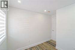 Neutral wall tones with wood-finish flooring, recessed lighting, and a window with horizontal blinds - 